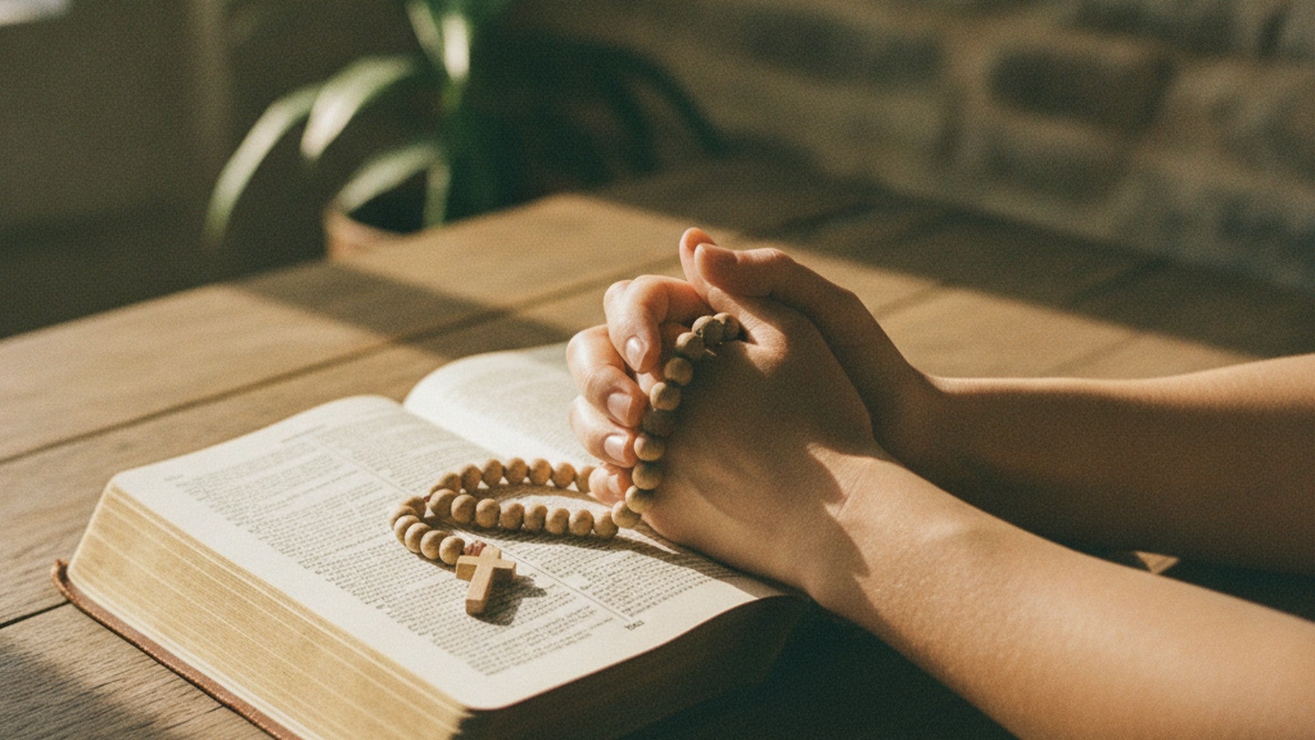 Deux mains posées sur une Bible ouverte, un chapelet de bois glissé entre les doigts, sur une table en bois