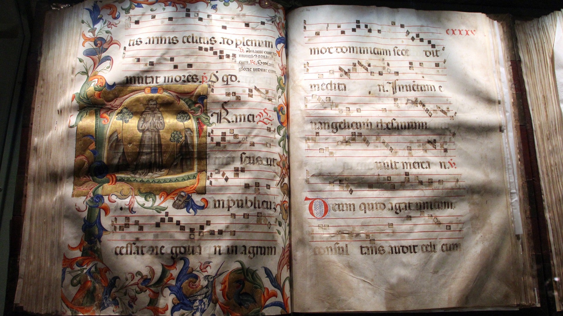 Antiphonaire ouvert sur un lutrin de bois sculpté, grands neumes carrés sur un parchemin ancien, stalles de chœur derrière