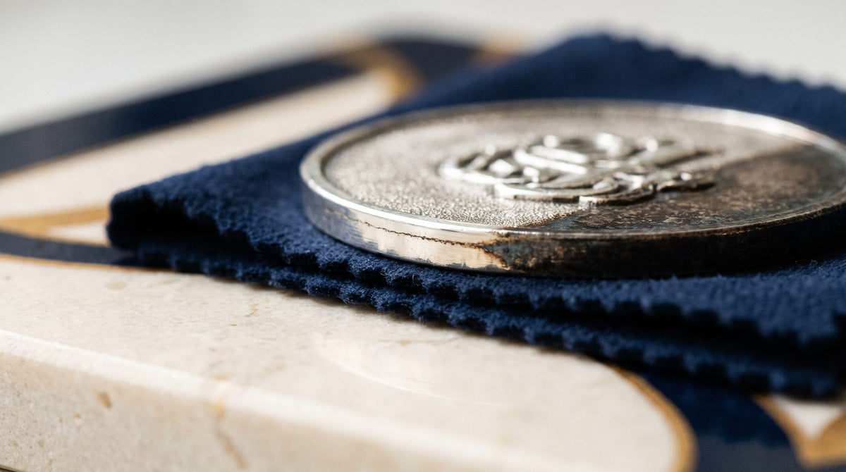 Entretenir un bijou en argent qui noircit : médaille à demi ternie sur un chiffon