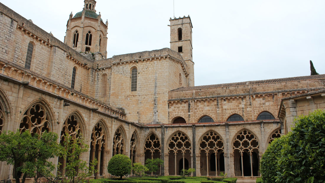Galerie couverte d'un cloître monastique, arcades romanes ouvrant sur un jardin ensoleillé avec un puits