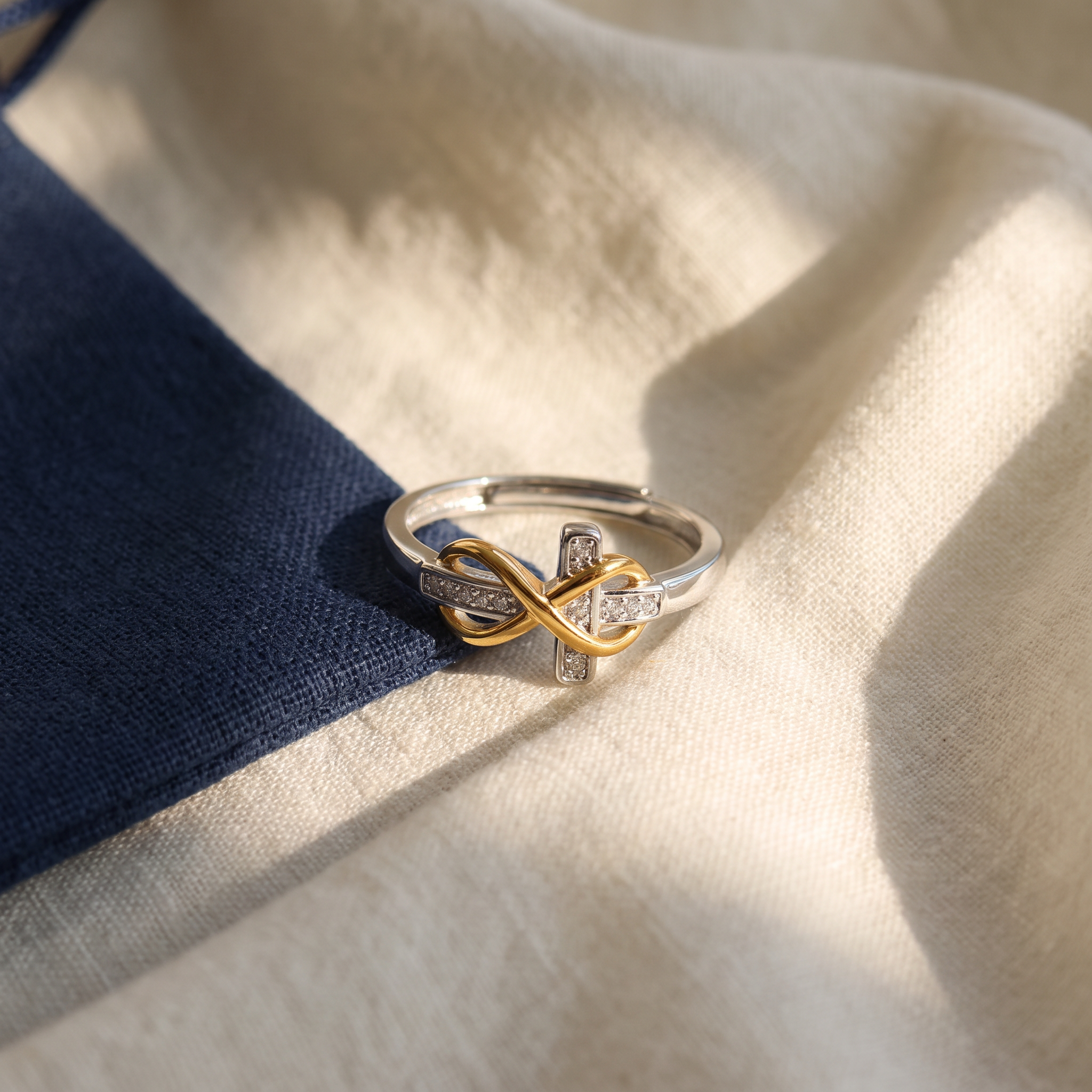 Bague croix infini - Perpétue posé sur du lin ivoire, pochon marine en accent