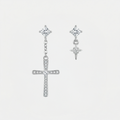 Boucles d'oreilles croix asymétriques, argentées, sur fond blanc