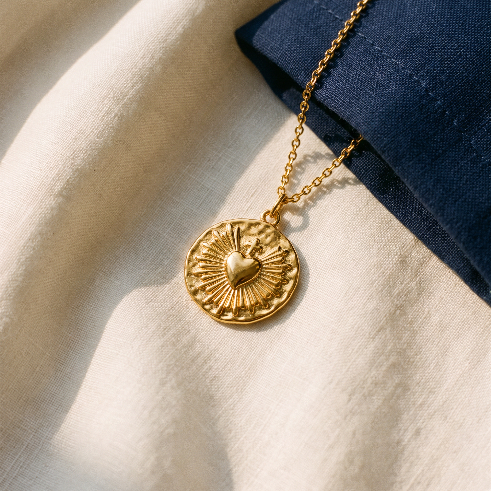 Collier Coeur Sacré - Marguerite posé sur du lin ivoire, pochon marine en accent