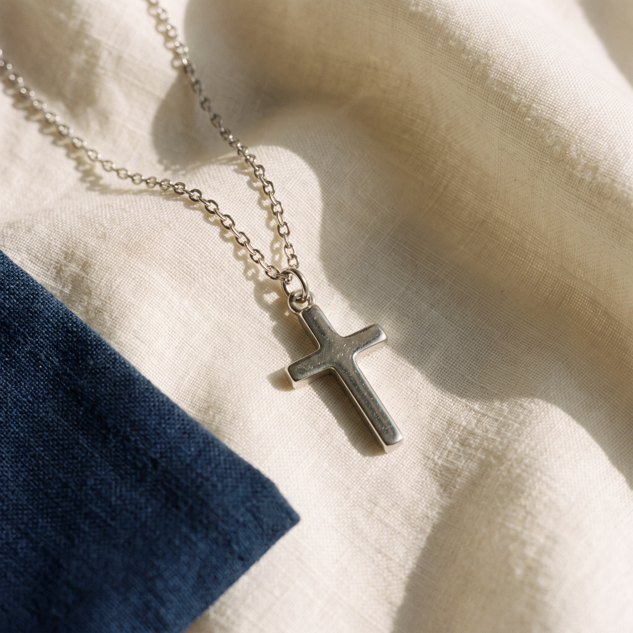 Collier croix de Jésus - Paul posé sur du lin ivoire, pochon marine en accent